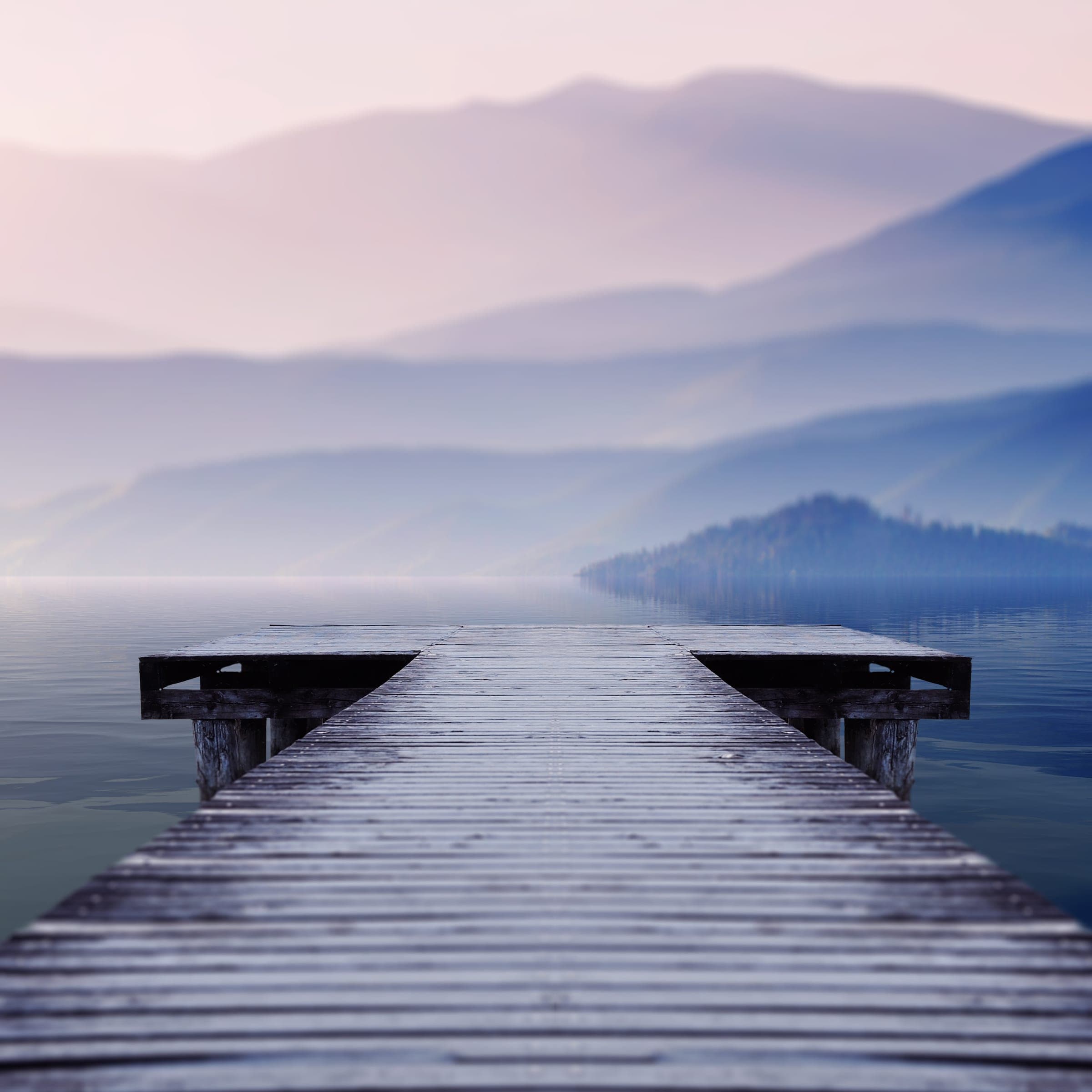 Steg an einem nebligen Bergsee im Morgenlicht